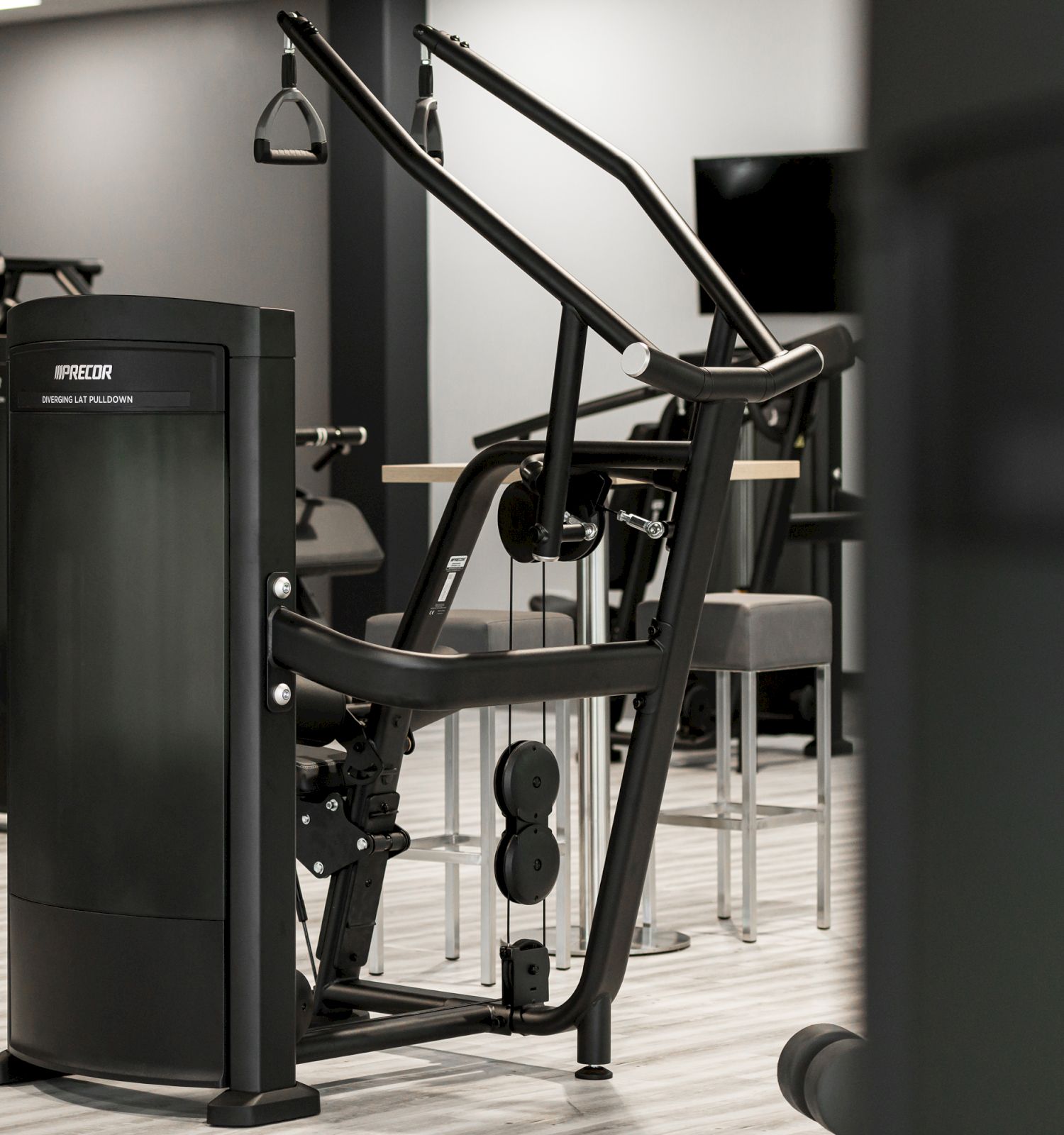 The image shows gym equipment, including a machine for workouts, in a fitness center setting, with a modern and clean design.