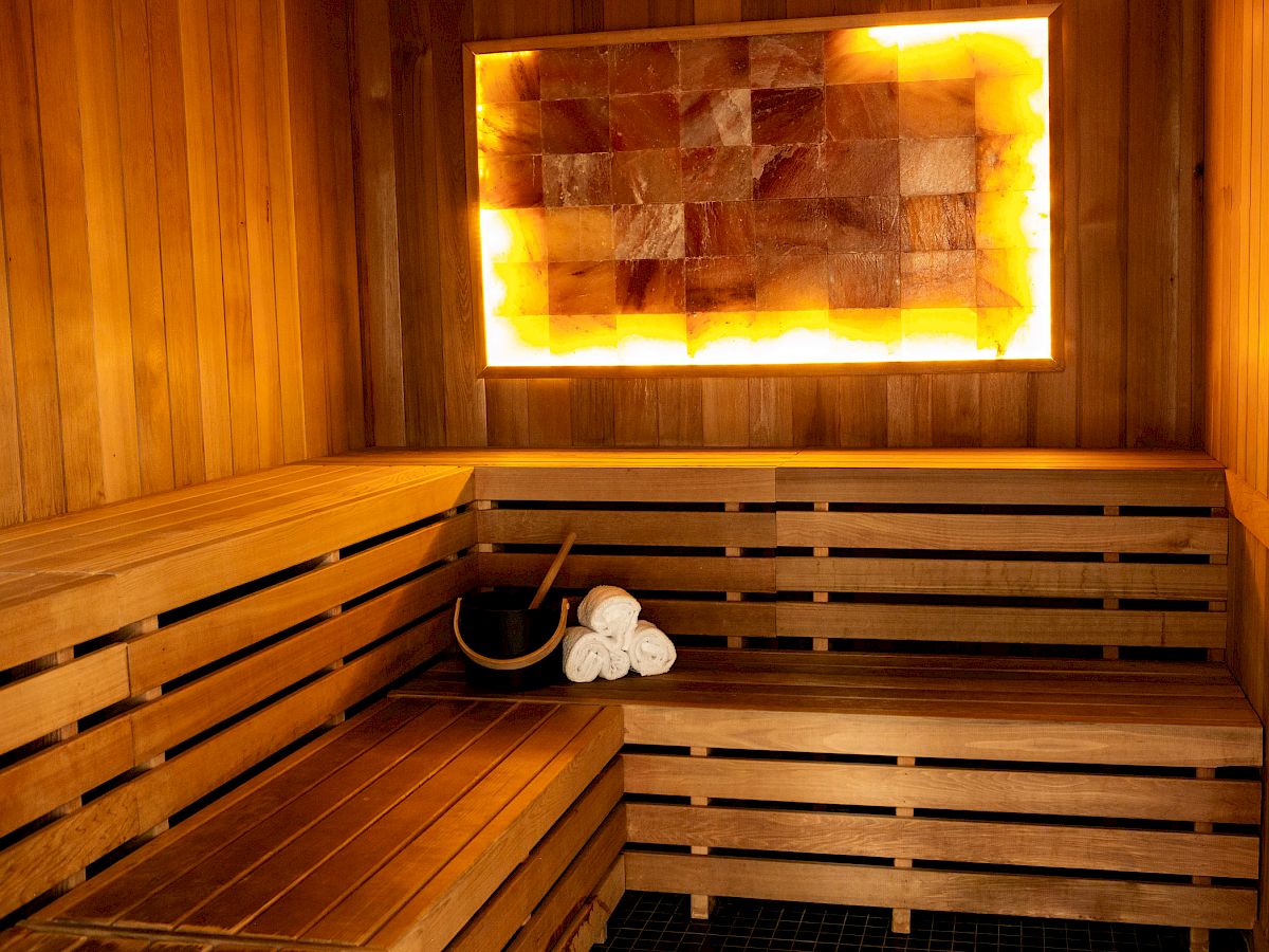 This image shows an interior of a wooden sauna with a glowing salt panel and towels on the bench.